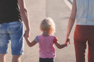 Two people holding hands with a small child family.