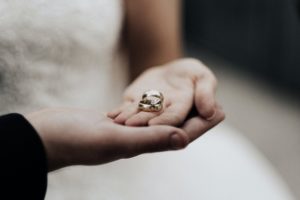 Spouses holding wedding rings in their hands.