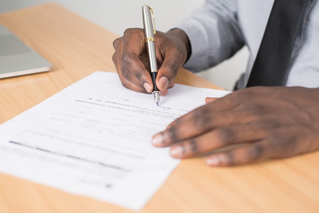Image of person signing a paper. Immigration appeals and litigation law firm.