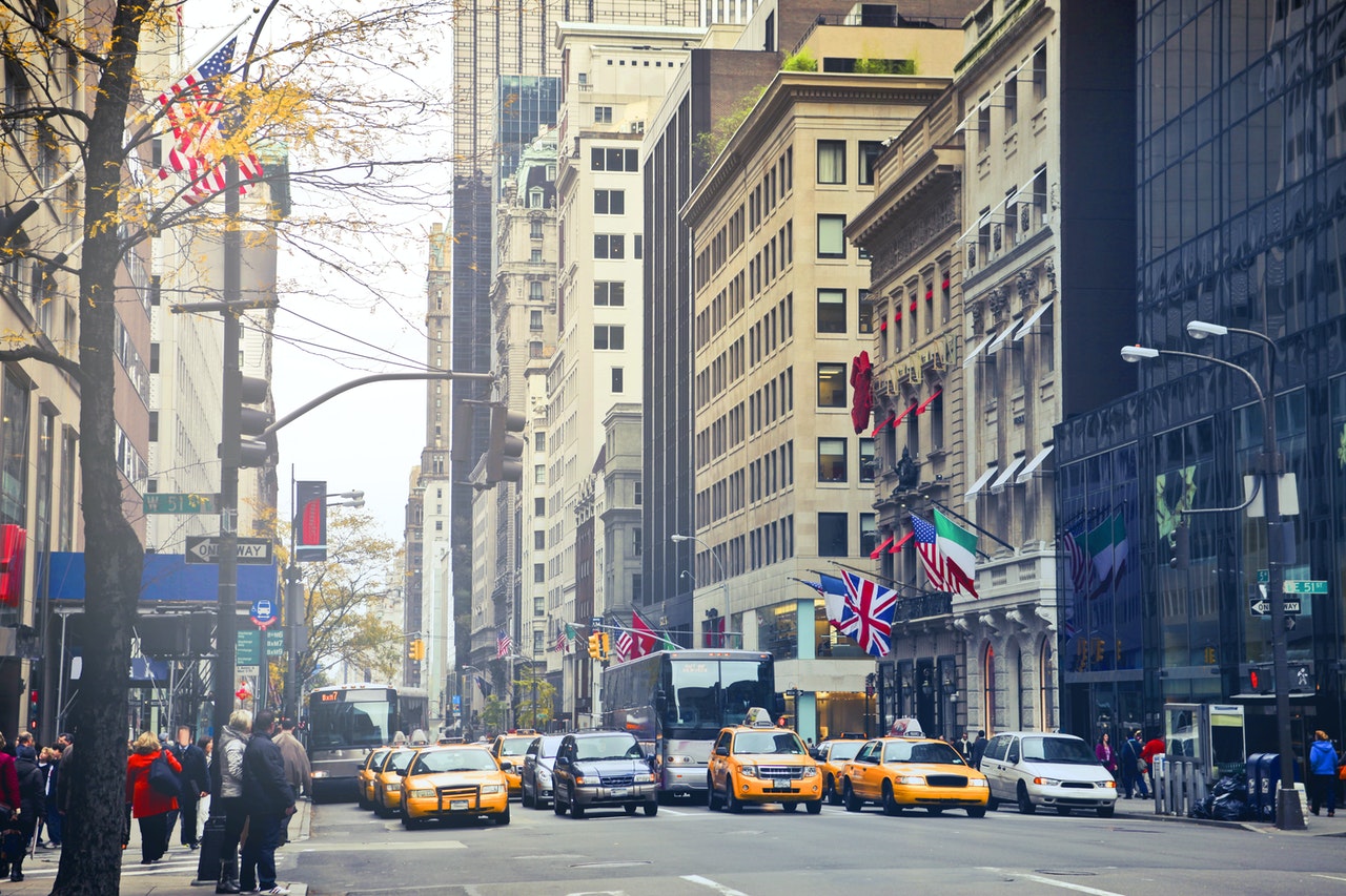 image of city with traffic, people, and international flags decorating buildings. Need an H-1B Visa Attorney? Hire us today.