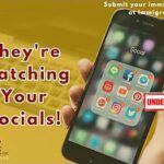 Image of cellphone with hand over gold faded background with a laptop. The words printed on the foreground next to the phone read "They're watching your socials!"