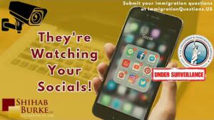 Image of cellphone with hand over gold faded background with a laptop. The words printed on the foreground next to the phone read "They're watching your socials!"