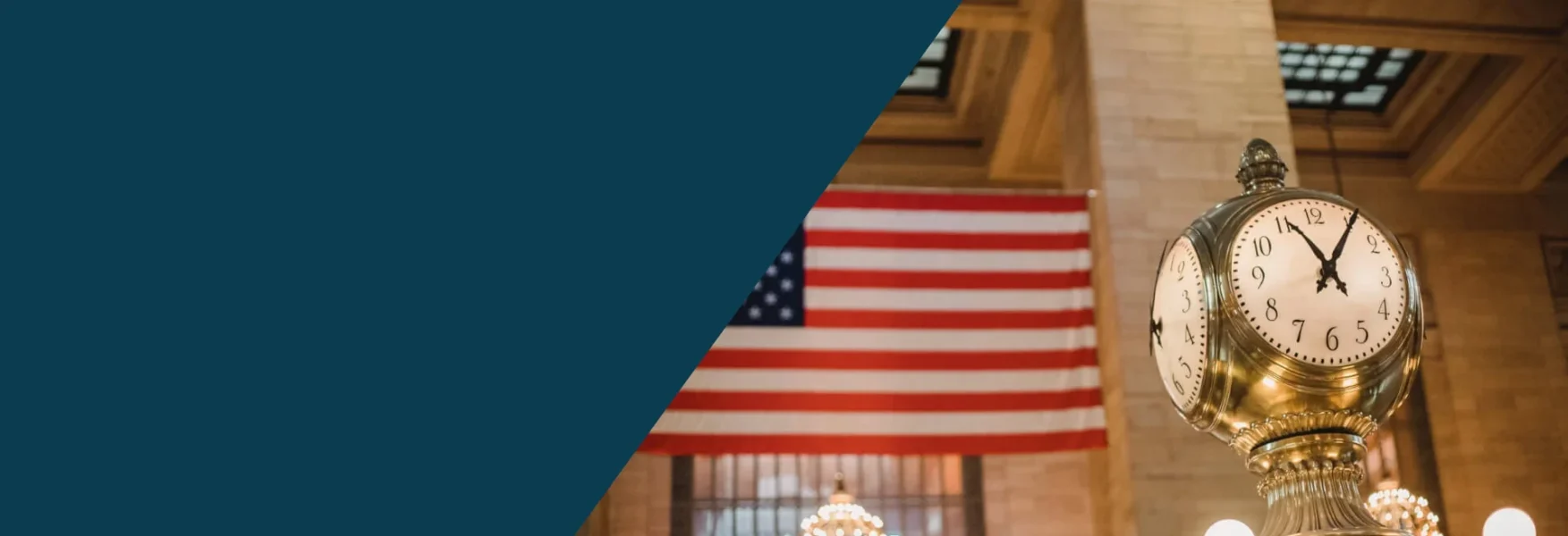 This is a banner image with half its left section colored in dark teal color and the other half there is an image of the Grand Central station clock and in the background there is the US flag along with the ceiling of the station. The image signifies the freedom an American flag represents along with the Shihab Burke LLC Immigration Lawyers brand.
