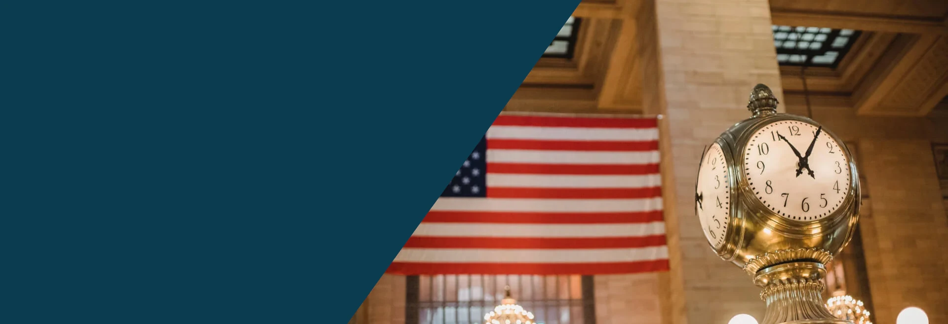 This is a banner image with half its left section colored in dark teal color and the other half there is an image of the Grand Central station clock and in the background there is the US flag along with the ceiling of the station. The image signifies the freedom an American flag represents along with the Shihab Burke LLC Immigration Lawyers brand.