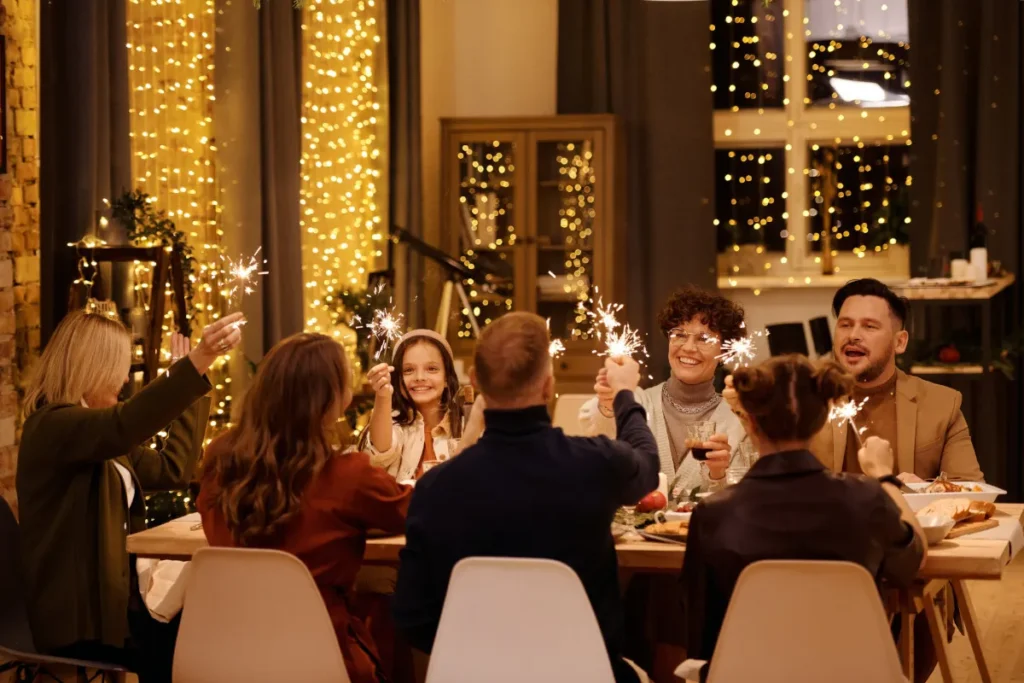 Image of family fathering around a dinner table. The family is at a restaurant and the family members are holding up glasses in celebration. The image represents family member immigration and re-union.