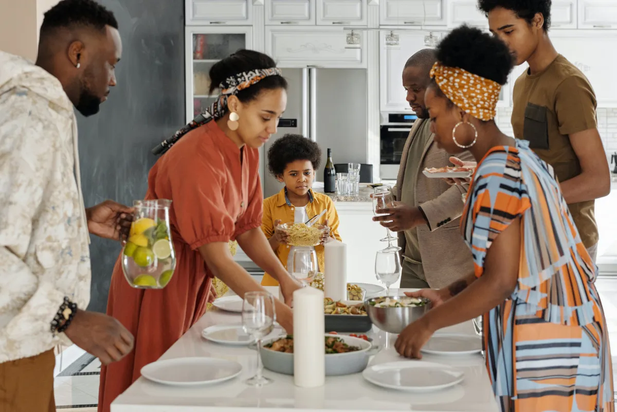 Image of a family getting ready to eat around a table. The family members are serving food on their plates. The image represents the other family member immigration preferences.