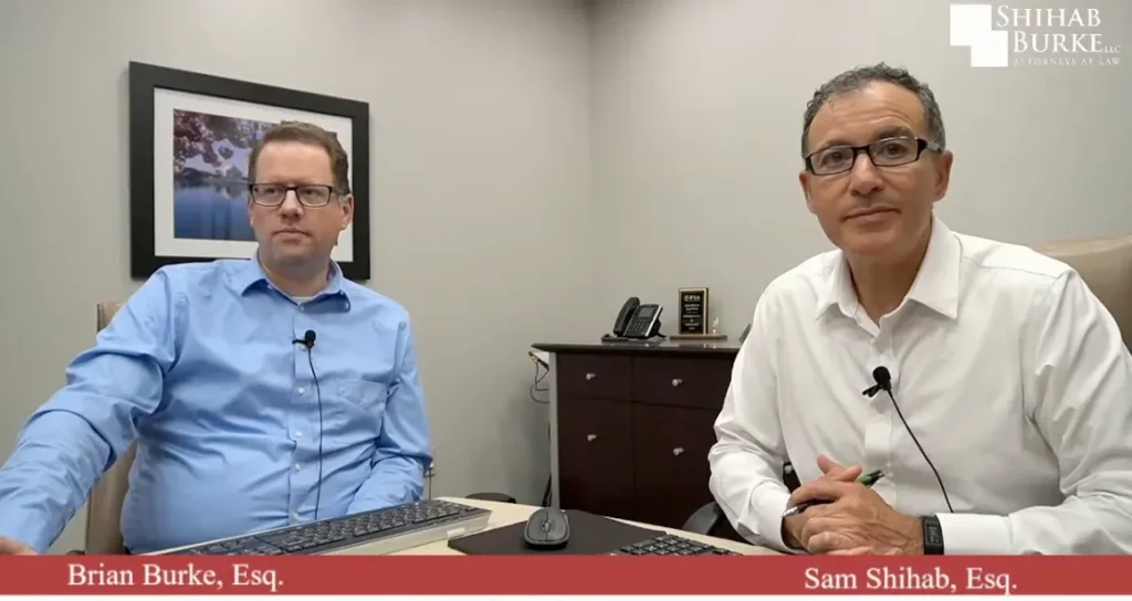 Image of Sam Shihab & Brian Burke talking about their H-1B Visa expertise in their YouTube Channel. Sam and Brian are sitting on desk in their office looking at the camera.
