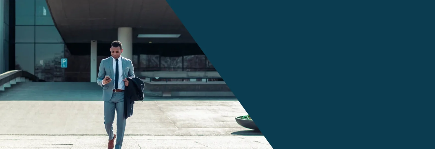 This is a banner image with half its right section colored in dark teal color and the other half there is an image of a man walking out of a train station with his briefcase in one hand his mobile phone on the other hand. The image signifies the freedom business men and woman have in the United States along with the Shihab Burke LLC Immigration Lawyers brand.