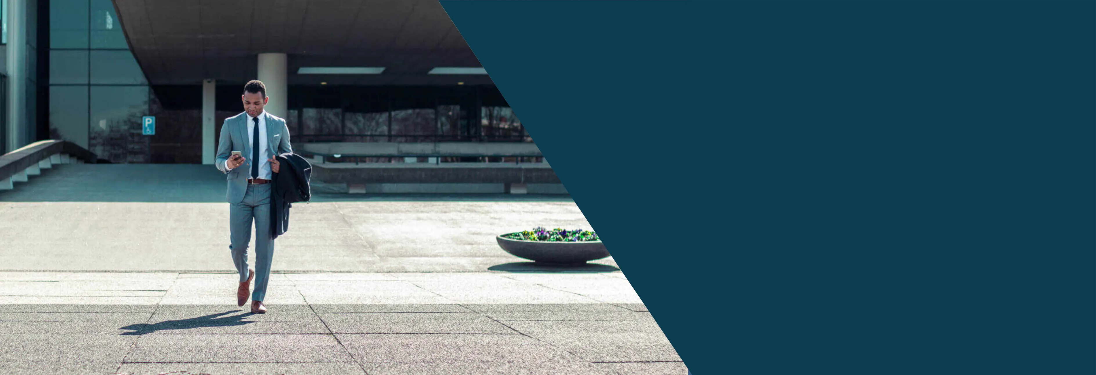 This is a banner image with half its right section colored in dark teal color and the other half there is an image of a man walking out of a train station with his briefcase in one hand his mobile phone on the other hand. The image signifies the freedom business men and woman have in the United States along with the Shihab Burke LLC Immigration Lawyers brand.